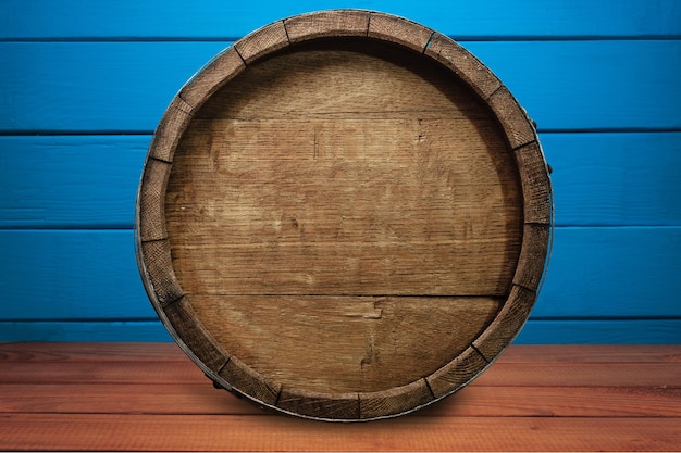 Beautiful wooden barrel on a red wood table and blue wood wall background