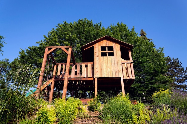 beautiful wooden children playhouse with swing and slide on hillside