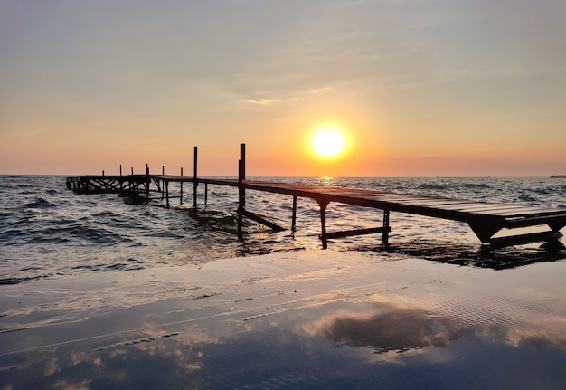 Beautiful wooden fishing pier at sunset on sea