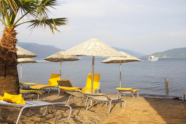 Marmaris 해변의 짚으로 만든 아름다운 노란색 의자 라운지와 우산