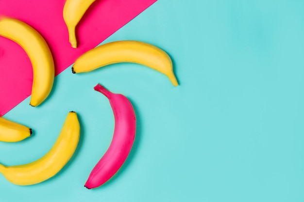 Beautiful yellow and one pink banana on a colorful background. From top view