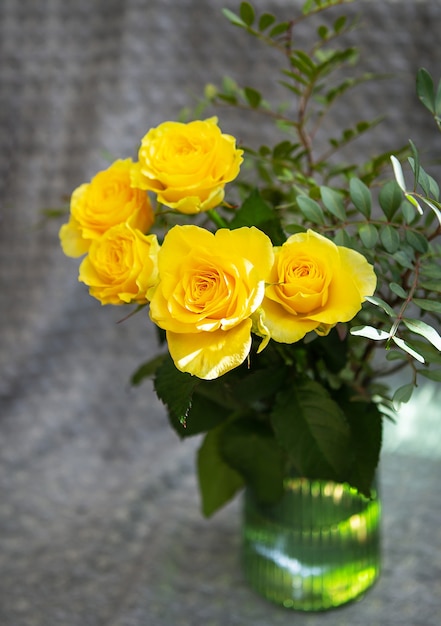 緑の花瓶に美しい黄色いバラが毛布の上に立っています。驚きと休日のコンセプト。