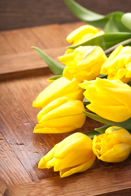 Beautiful yellow tulips are located on a wooden background