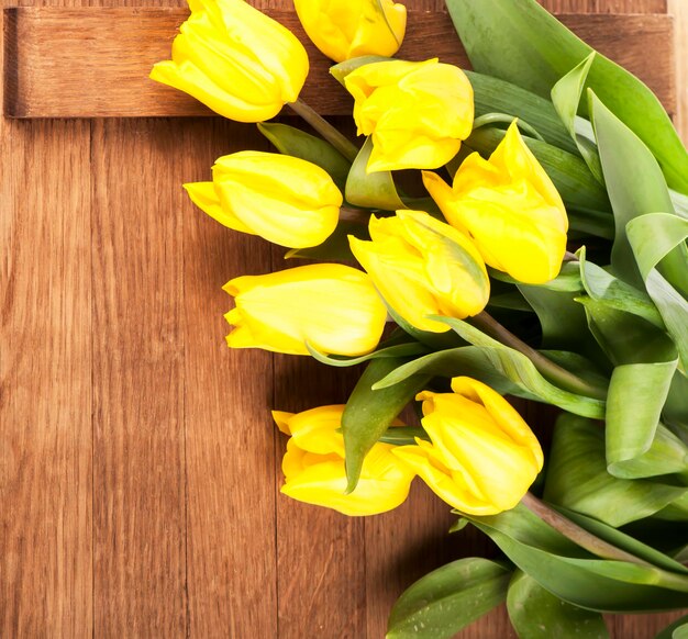 Beautiful yellow tulips are located on a wooden background