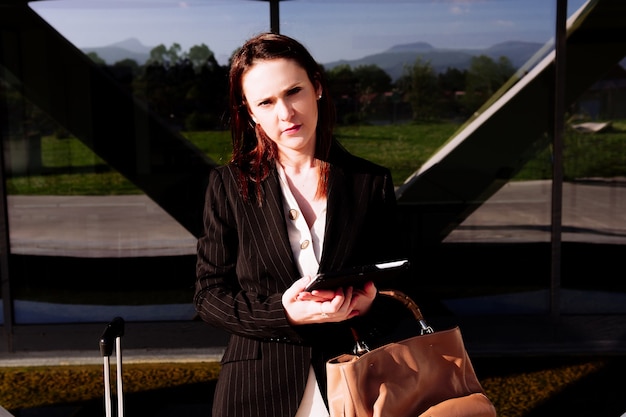 Beautiful young adult woman on business trip checking tablet on the street. business travel and connectivity concept