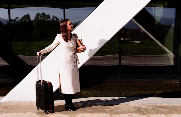 Foto bella giovane donna adulta in viaggio d'affari in attesa di trasporto guardandosi intorno nervosamente nell'area dell'ufficio sulla strada