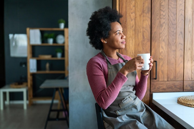 美しい若いアフリカ系アメリカ人女性がリラックスしながらコーヒーを飲んでいます