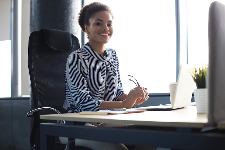 Photo beautiful young african american woman is sitting in the office and looking at camera.