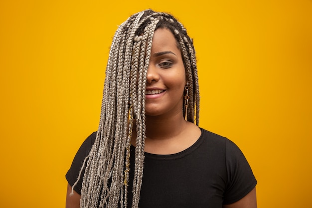 Beautiful young african american woman with dread hair on yellow