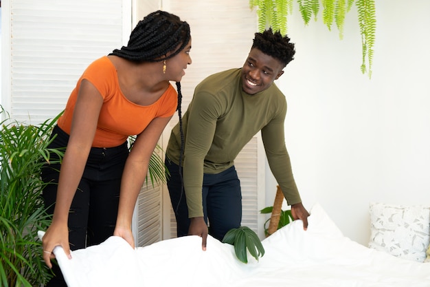 침실에서 침대를 만드는 아름 다운 젊은 아프리카 부부