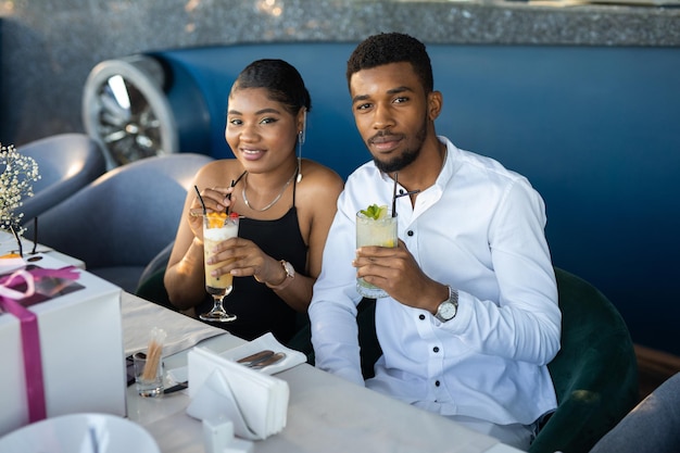 beautiful young african couple in a restaurant with drinks