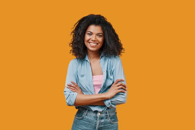 Bella giovane donna africana in abbigliamento casual che guarda l'obbiettivo e sorridente