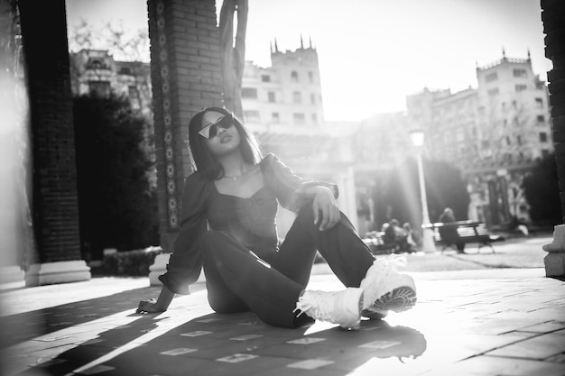 A beautiful young African woman in a park lifestyle Fashionably posed sitting on the floor in black and white