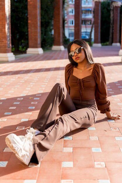 A beautiful young African woman in a park lifestyle Fashionably posed sitting on the ground at sunset