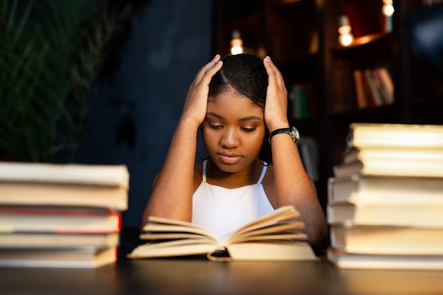 beautiful young african woman reading a book in the library