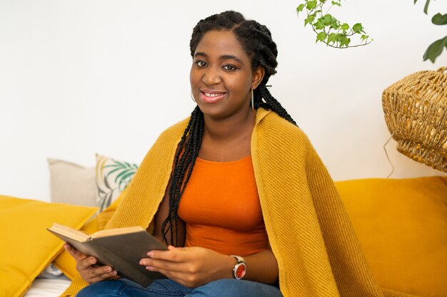 beautiful young african woman sitting on bed with a book