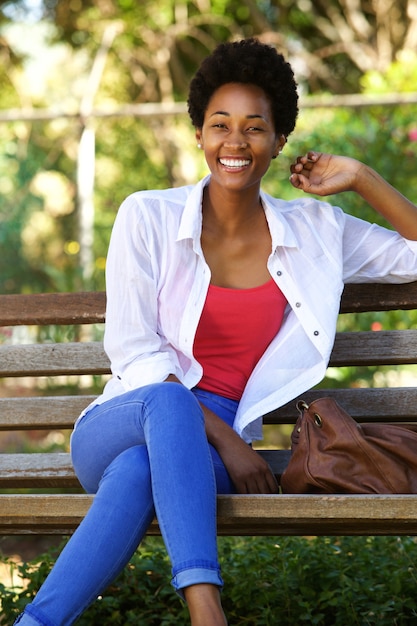 Красивая молодая африканская женщина, сидя на скамейке в парке