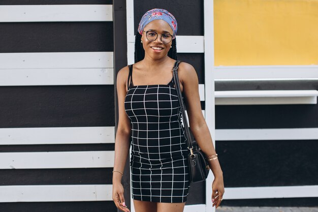 Beautiful young african woman wearing fashionable dress posing on the street. Afro hairstyle