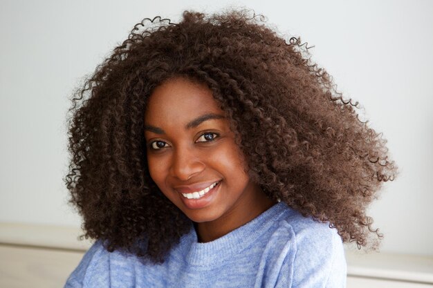 Photo beautiful young african woman with curly hair looking at camera with smile on face