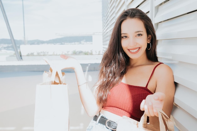 Beautiful young african woman with shopping bags on city street mall. Copy space, Christmas new year shopping presents concept, new clothes shopping day. Modern styling and young woman concepts