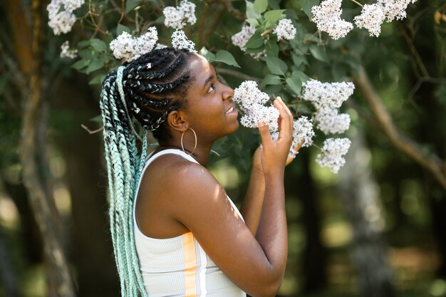 木の上の春の花を持つ美しい若いアフリカの女性