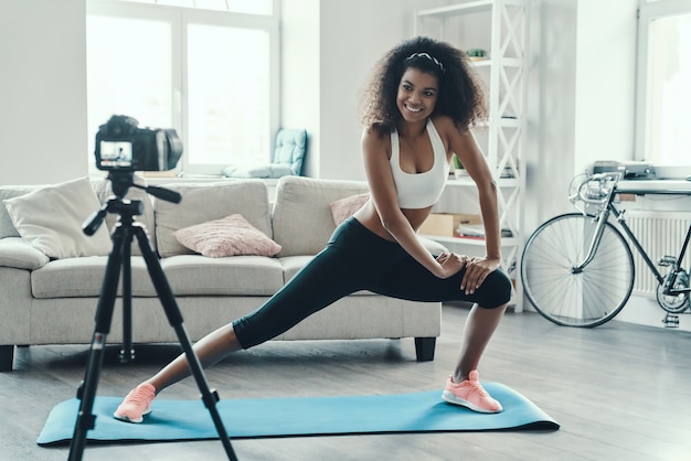 Beautiful young African woman working out and smiling while making social media video