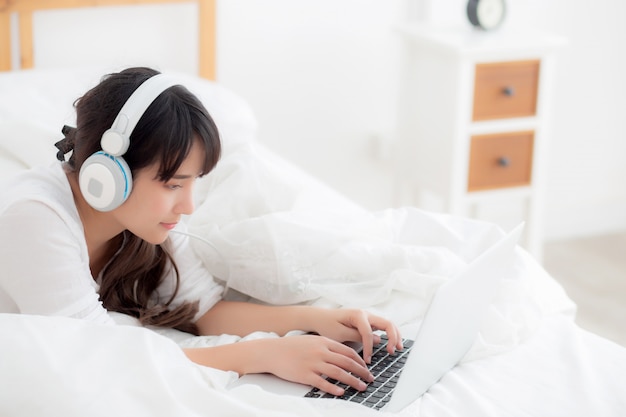 Beautiful young asia woman lying in bedroom using laptop