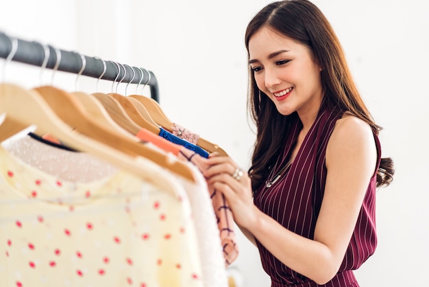 아름 다운 젊은 아시아 여자 쇼핑 및 store.fashion 쇼핑 개념에서 옷을 선택