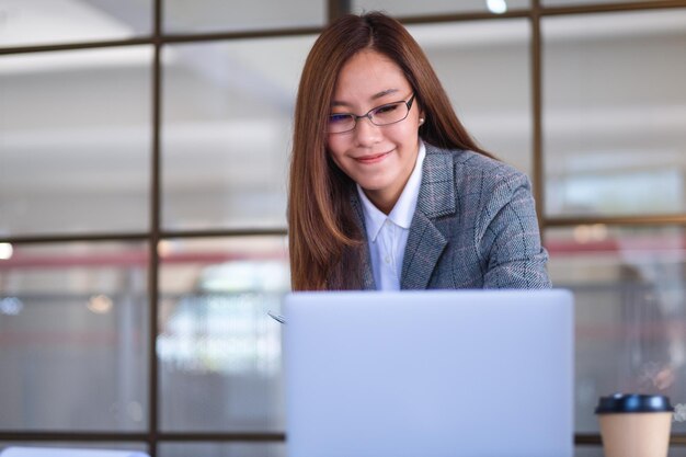 사무실에서 일하는 동안 노트북 컴퓨터를 사용하는 아름다운 젊은 아시아 여성