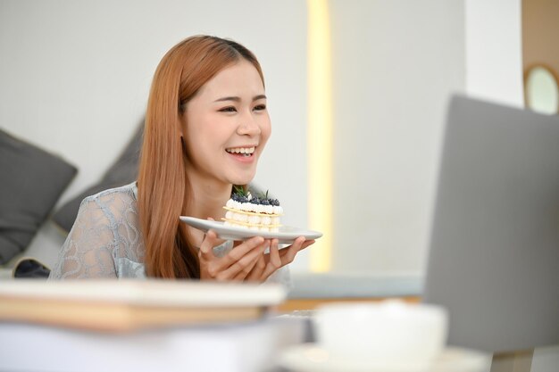 Beautiful young Asian female food blogger in the cafe reviewing a delicious cake