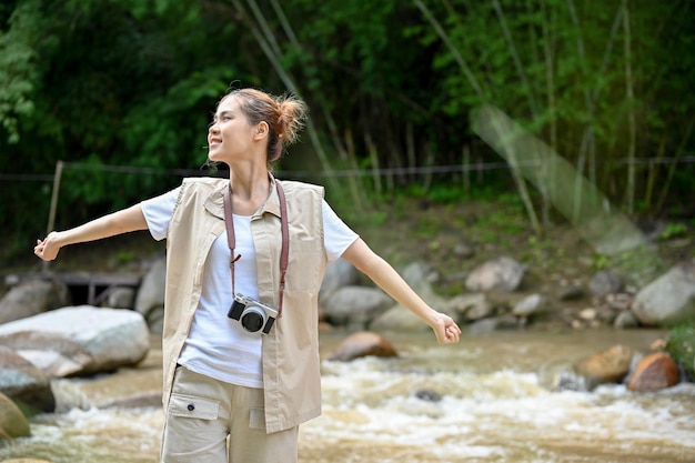 Красивая молодая азиатская путешественница, стоящая у реки и подышающая свежим воздухом