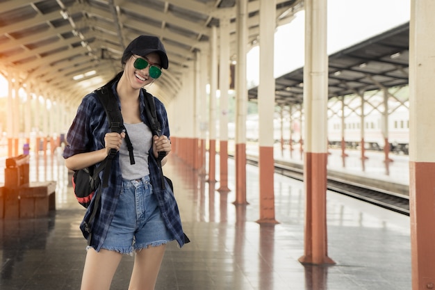 Bella ragazza asiatica giovane che viaggia da solo alla stazione ferroviaria