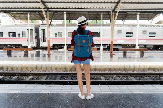 列車の駅で一人で旅行する美しい若いアジアの女の子