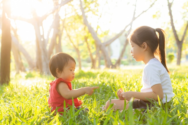 여름에 아름 다운 젊은 아시아 아이 앉아 연주