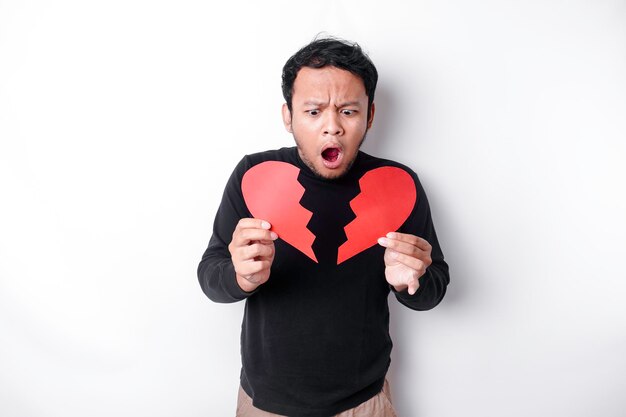 Beautiful young Asian man expressed his sadness while holding broken heart isolated on white background