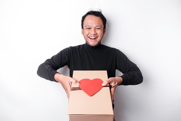 Beautiful young Asian man wearing black shirt holding gift box red heart Valentine39s Day concept