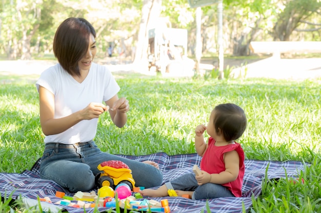 Belle giovani mamma e figlia asiatiche che giocano i blocchetti del giocattolo per l'apprendimento dello sviluppo felice