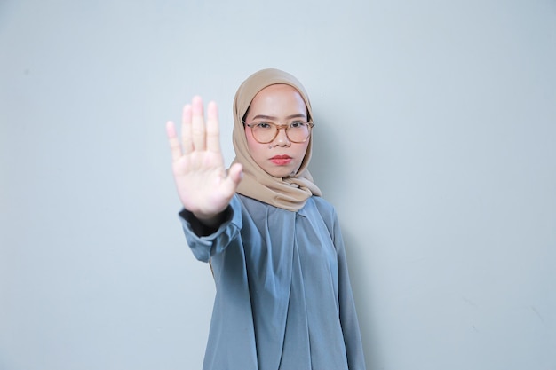 Beautiful young Asian muslim business woman wearing glasses pointing stop gesture