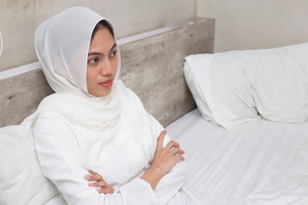 Beautiful and young asian muslim woman  sitting on bedroom