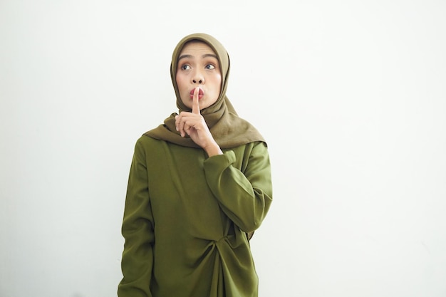Красивая молодая азиатская мусульманка в повседневной одежде просит тишины с пальцем на губах