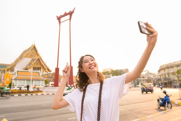 Beautiful young Asian tourist woman on vacation sightseeing and exploring Bangkok city