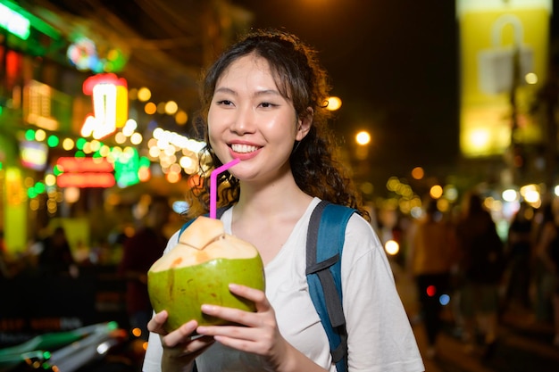 Beautiful young Asian tourist woman on vacation sightseeing and exploring at Khao San road at night in Bangkok city Thailand Holidays and traveling concept