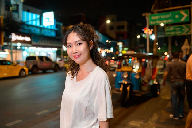 Beautiful young Asian tourist woman on vacation sightseeing and exploring at Khao San road at night