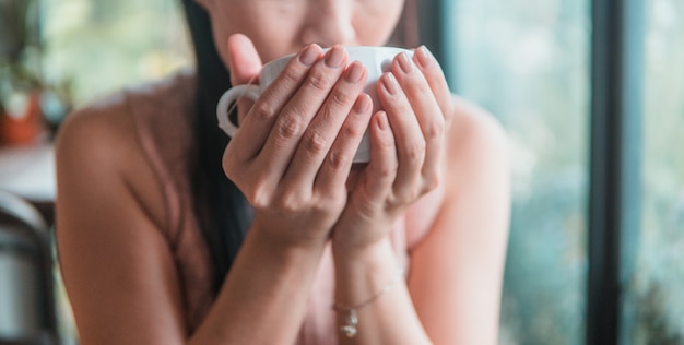 コーヒーを飲みながらカフェで美しい若いアジア女性。