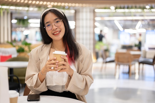 Foto una bella giovane donna asiatica in abbigliamento casual è seduta in un caffè nel centro commerciale