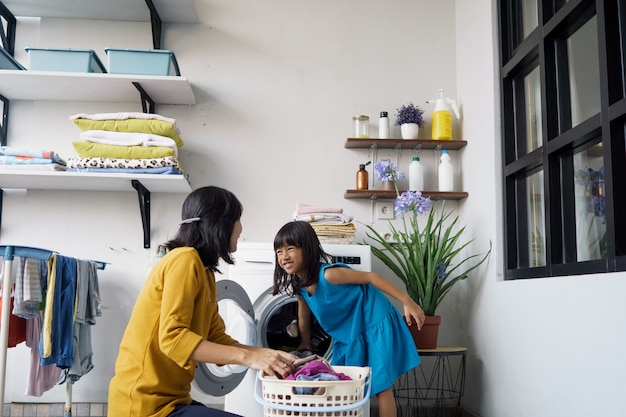 Beautiful young asian woman and child girl little helper are doing laundry at home.