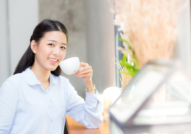 カフェでコーヒーを飲む美しい若いアジアの女性。