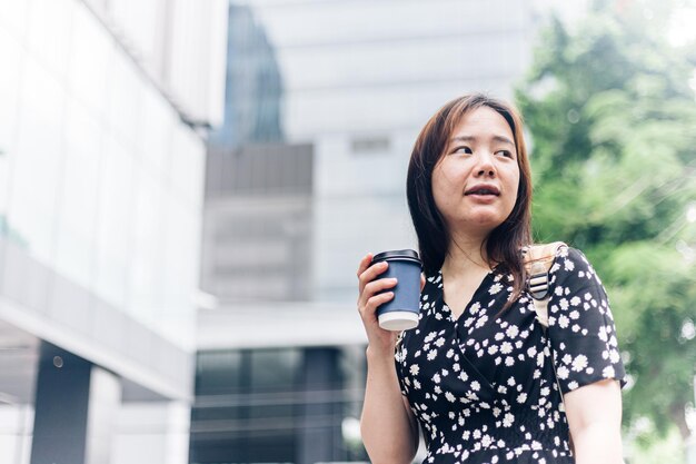 市内の道路でコーヒーを飲む美しい若いアジア人女性