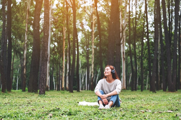 A beautiful young asian woman enjoy listening to music with headphone with feeling happy and relaxed in the park