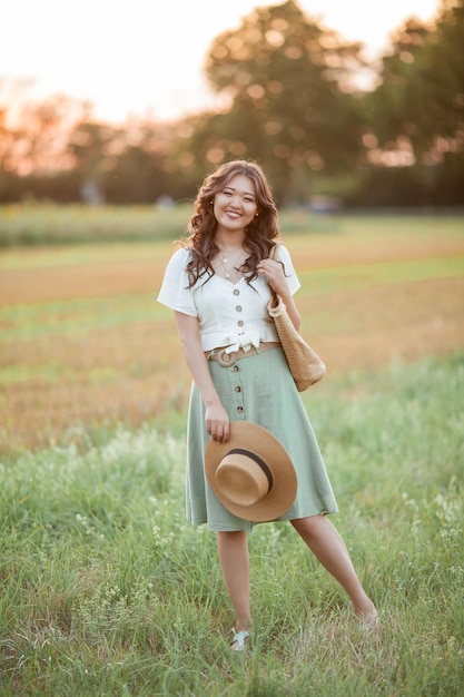 Photo beautiful young asian woman in field at sunset model with dark long curly hair summer